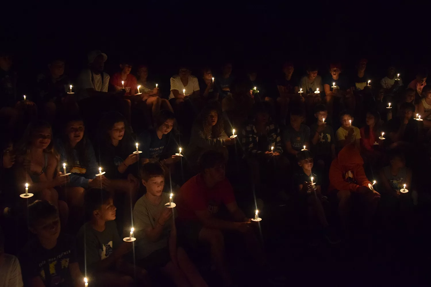 Campers holding candles after dark